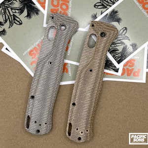 May include: Two beige and brown patterned knife scales with a textured surface. The scales are made of G10 material and have a unique pattern. The scales are for a folding knife.