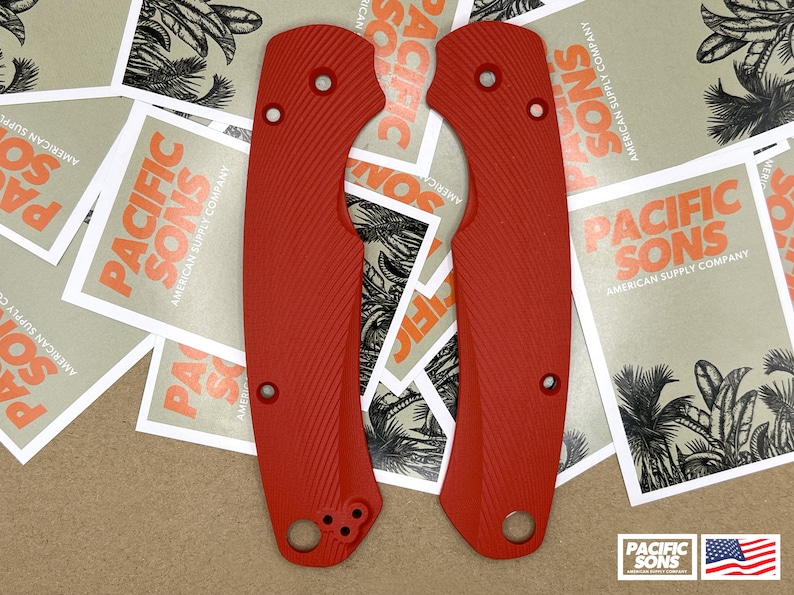 May include: Two red, textured, plastic knife scales with a Pacific Sons logo. The scales have a textured pattern and are designed to fit a knife handle.