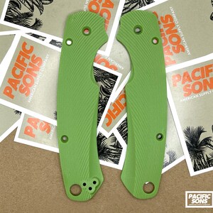 May include: Two green textured knife scales with a hole for a pivot pin and three screw holes. The scales are made of a durable material and are designed to fit a specific knife model.