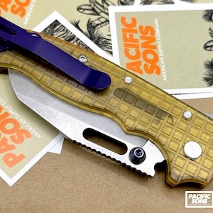 May include: A folding pocket knife with a translucent yellow grid-patterned handle and a metallic silver blade. The knife features a dark blue pocket clip attached to the handle with silver screws and a thumb stud on the blade for opening.