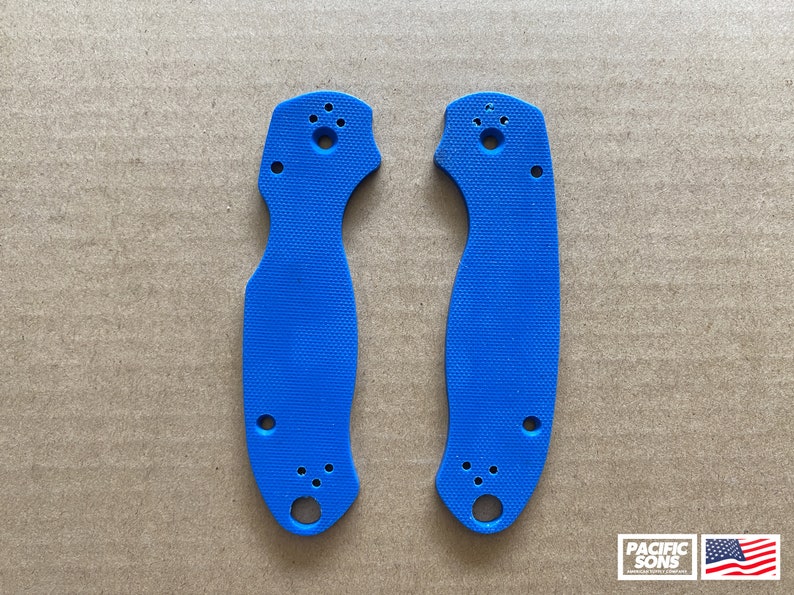 May include: Two blue plastic knife scales with holes for mounting hardware. The scales are textured and have a slightly curved shape.