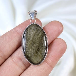 May include: Oval-shaped pendant with a silver-colored bail and frame. The pendant features a polished, golden-brown stone with a shimmering effect. The stone is set in a simple, elegant design, suitable for everyday wear.