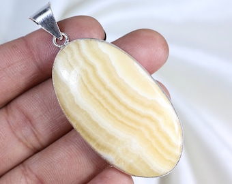 Può includere: Ciondolo ovale con anello argentato. Il ciondolo presenta una pietra color crema con motivi ondulati marrone chiaro. La pietra è incastonata in una cornice di metallo argentato. Per collane.