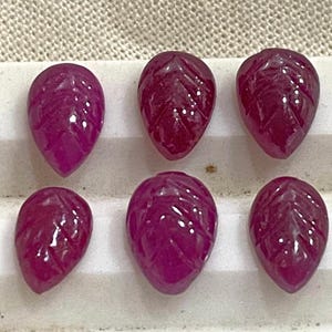 Peut inclure: Six pierres précieuses de rubis roses sculptées en forme de feuille. Les pierres précieuses sont facettées et ont une finition brillante.