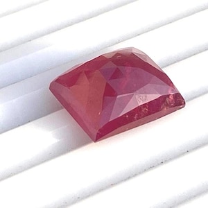 May include: A deep red gemstone with a square shape and a faceted cut.
