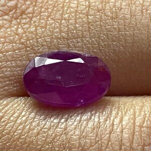 Könnte beinhalten: Ein lebendiger, ovaler Edelstein in Violett mit facettiertem Schliff.