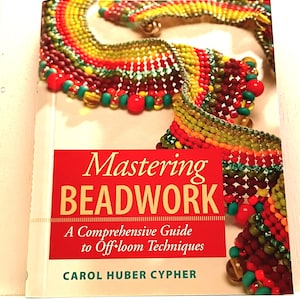 May include: A book titled "Mastering Beadwork" with a red banner and white text. The book cover features a colorful beaded necklace in shades of red, yellow, green, and brown. The book is a comprehensive guide to off-loom techniques.