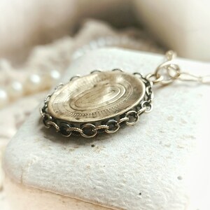 May include: A gold-toned locket with a detailed spiral design on the front. The locket is attached to a chain with a decorative clasp.