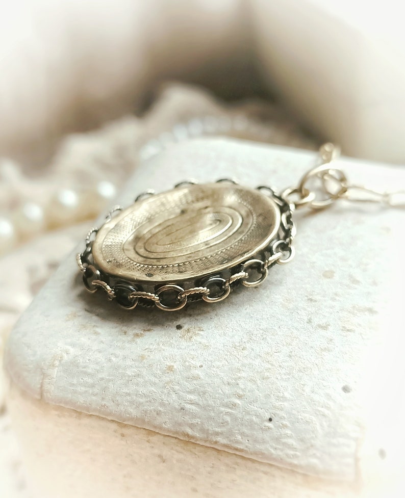 May include: A gold-toned locket with a detailed spiral design on the front. The locket is attached to a chain with a decorative clasp.