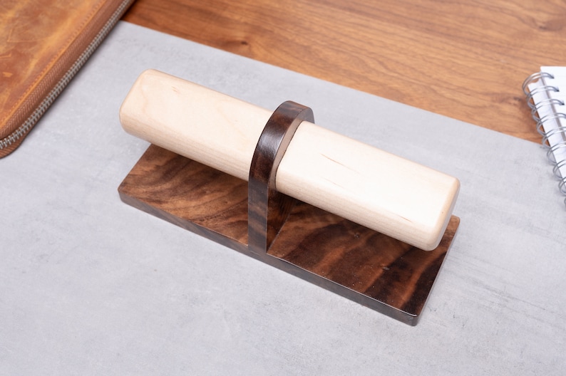 May include: A wooden pen holder with a light brown cylindrical base and a dark brown walnut base.