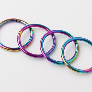 May include: Four rainbow-colored metal hoop earrings of different sizes.