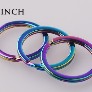May include: Three iridescent key rings, each with a 1 inch diameter, are stacked on top of each other. The key rings are a rainbow of colors, including purple, blue, green, and yellow.