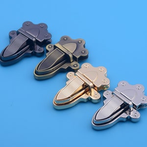 May include: Four decorative metal clasps in different finishes: black, antique brass, gold, and silver. Each clasp has a flower-shaped design with a textured surface.