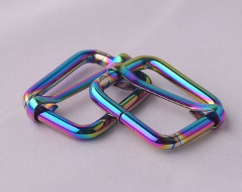 Op de afbeelding: Twee regenboogkleurige metalen D-ringen, waarbij de ene over de andere ligt.