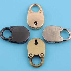 May include: Four small decorative padlocks in different finishes: gold, silver, black, and antique brass. Each padlock has a keyhole and a small loop for attaching to a bag or other item.
