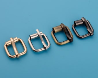 May include: Four metal belt buckles in different finishes: gold, silver, antique brass, and black. The buckles are all the same size and shape, with a square frame and a rounded opening.