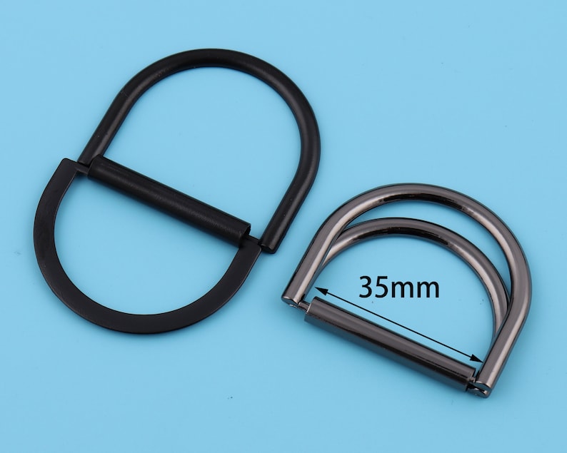 May include: Two black metal D-rings, one with a 35mm diameter, for attaching to bags, belts, or other accessories.