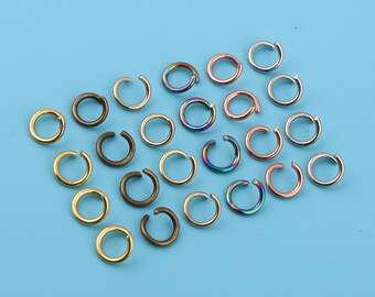 May include: Assortment of jump rings in various colors and finishes, including silver, gold, bronze, and rainbow. The jump rings are arranged in rows on a blue background.