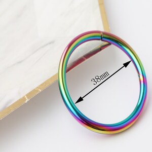 May include: A rainbow-colored metal ring with a diameter of 38mm. The ring is smooth and shiny.