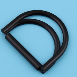 May include: Black metal D-ring with a double loop. The ring is about 2 inches in diameter.