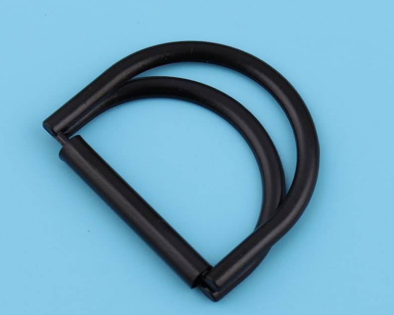May include: Black metal D-ring with a double loop. The ring is about 2 inches in diameter.