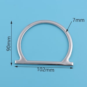 May include: Silver metal ring with a 7 mm width and a 102 mm diameter. The ring is a simple, circular shape with a flat, straight bar across the bottom.