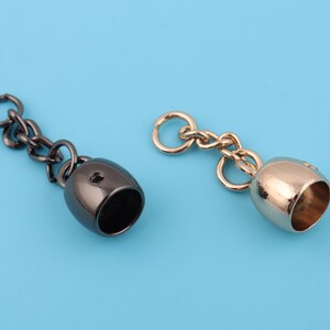 May include: Two metal chain end caps, one black and one gold, with a small chain attached to each.