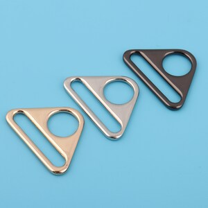 May include: Three triangle-shaped metal clasps in gold, silver, and black.