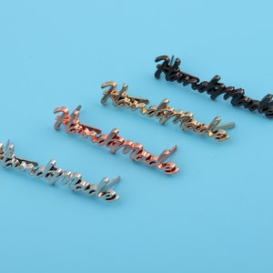 Puede incluir: Cuatro etiquetas metálicas "Handmade" en diferentes acabados: plata, oro, oro rosa y negro.