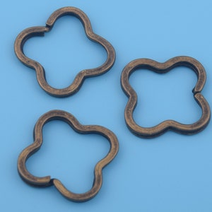 May include: Three antique gold-colored metal flower-shaped key rings.