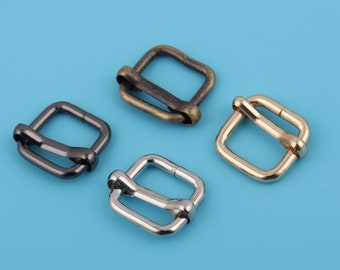 May include: Four metal belt buckles in different finishes: gold, silver, black, and antique brass. The buckles are square shaped with a rounded edge and a smooth finish.