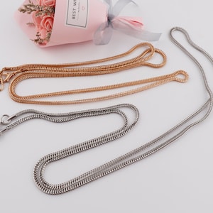 Puede incluir: Dos collares de cadena, uno dorado y otro plateado, con cierres de langosta. Las cadenas son de doble capa y tienen un diseño delicado y tejido.