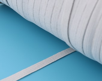 Op de afbeelding: Een close-up van een wit elastiek dat op een blauwe ondergrond is opgerold. Het elastiek is gemaakt van een zacht, rekbaar materiaal en is perfect voor naaiprojecten.
