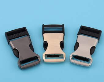 Op de afbeelding: Drie plastic schuifgespen in zwart, goud en zilver. De gespen zijn ontworpen voor gebruik met band of riemen.