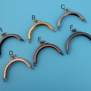 Puede incluir: Seis marcos de bolso de metal diferentes en varios acabados, incluyendo oro, plata y bronce. Los marcos son todos del mismo tamaño y forma, con una parte superior redondeada y una parte inferior plana. Están diseñados para ser utilizados para hacer bolsos, carteras y otras bolsas pequeñas.