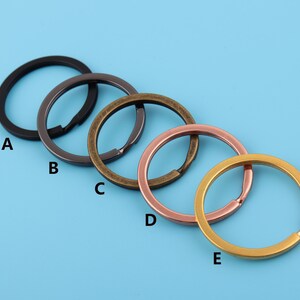 May include: Five key rings in different finishes: black, gunmetal, brass, rose gold, and gold.