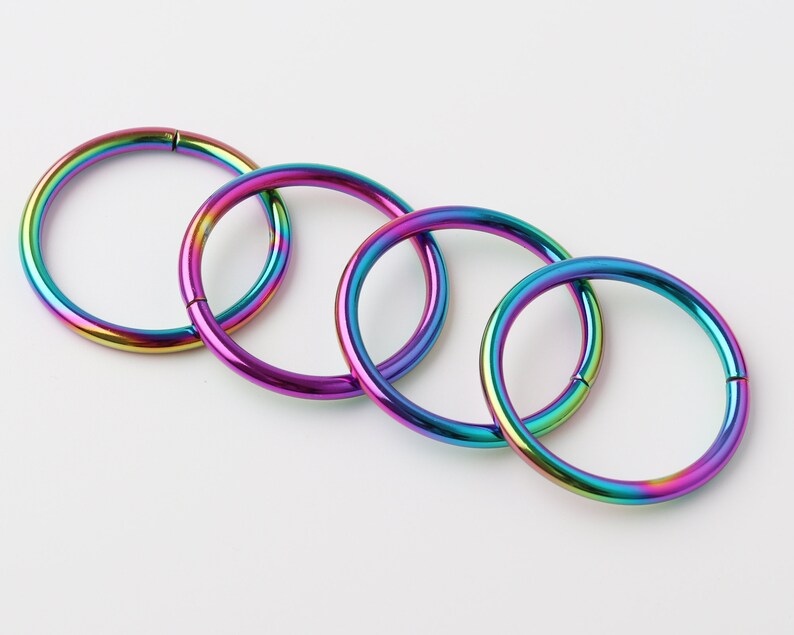 May include: Four rainbow-colored metal hoop earrings of different sizes.