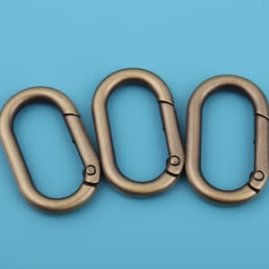 Könnte beinhalten: Drei antike, ovalförmige Verschlüsse aus goldfarbenem Metall mit einem Federverschluss.