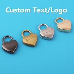 Peut inclure: Cadenas en forme de cœur dans différentes finitions métalliques : noir, or, argent et or avec une bordure turquoise. Les cadenas ont une fermeture à boucle et le texte "Custom Text/Logo" est affiché au-dessus sur un fond bleu.