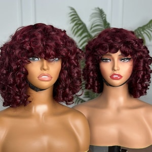 Puede incluir: Dos cabezas de maniquí con pelucas cortas y rizadas de color burdeos. Las pelucas tienen raya lateral y flequillo.