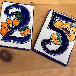 May include: Four ceramic tiles with blue numbers 2023 and floral designs in orange, yellow, and green.