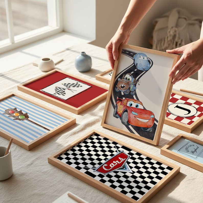 May include: A collection of framed art prints with a racing theme. One print features the word "Cars" on a checkered flag design. Other prints include a checkered flag, a traffic light, and a race car illustration. The frames are made of light-colored wood.