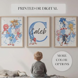 May include: Three framed prints featuring Sonic the Hedgehog characters. The prints have a light wood frame and a white background with blue paint splatters. One print has the name "Caleb" with a blue "C". The top text reads "PRINTED OR DIGITAL".