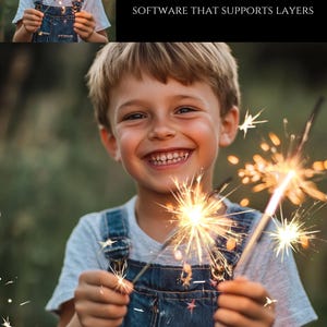 May include: A young boy smiles while holding two sparklers, one in each hand. The sparklers are lit and creating a bright, golden glow. The boy is wearing a blue denim overall and a white t-shirt. The background is a blurred green field.