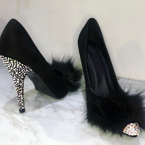 May include: A pair of black high-heeled shoes with a faux fur trim and a crystal-encrusted heel.