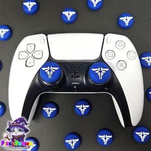 May include: A white and black PlayStation 5 controller with blue thumb grips featuring a white graphic design. Several matching blue thumb grips are scattered around the controller on a dark surface. The Pixel Potion logo is in the lower left corner.
