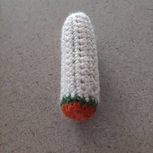May include: A crocheted white, green, and orange finger puppet shaped like a carrot.