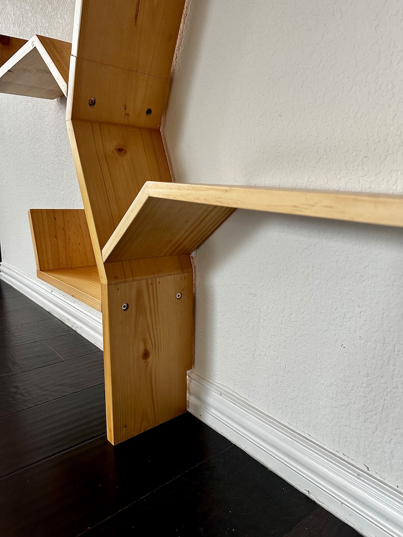 Op de afbeelding: Een zeshoekige houten plank met meerdere planken. De plank is gemaakt van natuurlijk hout en heeft een lichtbruine afwerking. De planken zijn schuin en cre&euml;ren een uniek geometrisch ontwerp.