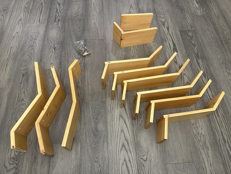 Op de afbeelding: Een set onafgewerkte houten plankensteunen, klaar om te beitsen of te schilderen. De steunen zijn in verschillende maten en vormen, sommige met een gebogen ontwerp.