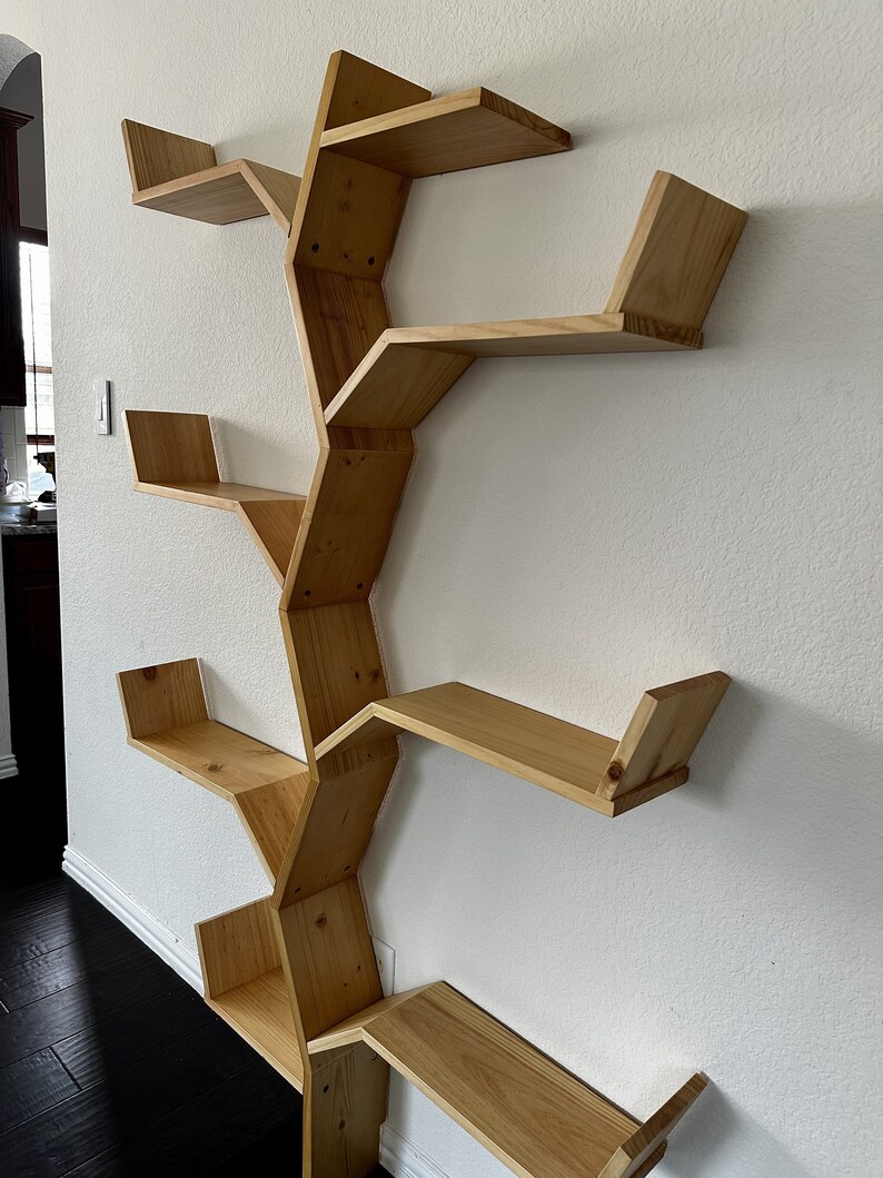 Op de afbeelding: Een houten wandplank in de vorm van een boom met meerdere takken en planken. De planken zijn gemaakt van natuurlijk hout en hebben een lichtbruine afwerking.